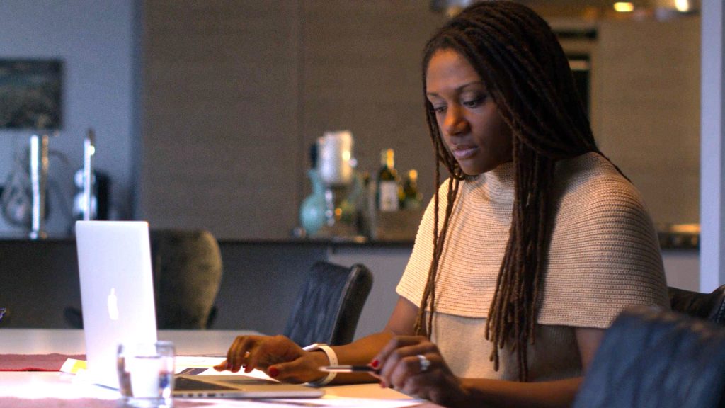 Snapshot from AwareGO cybersecurity awareness training video about insider risk when working from home. A woman is working with sensitive data at her dining room table.