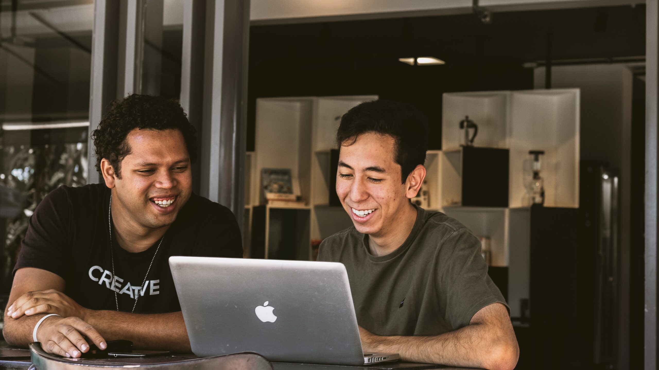 Two young men sitting at a desk and completing cyber security awareness training for small businesses on a laptop