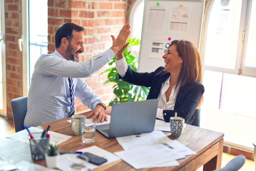Two coworkers in an office high-fiving for completing gamified cybersecurity training