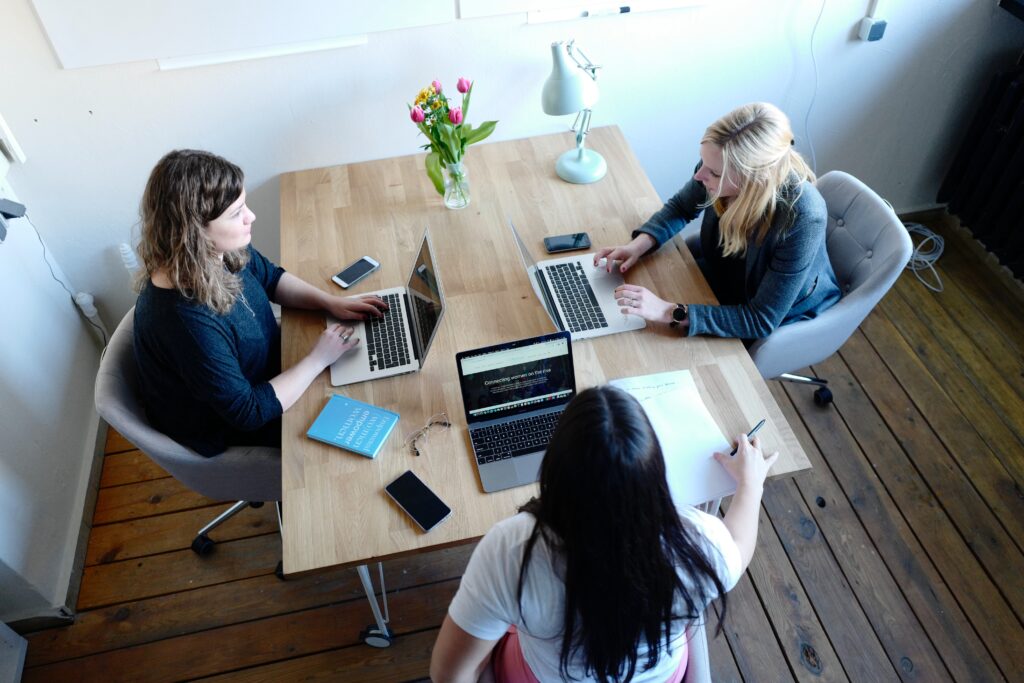 3 women sitting around a table on computers choosing the best security awareness training for their team